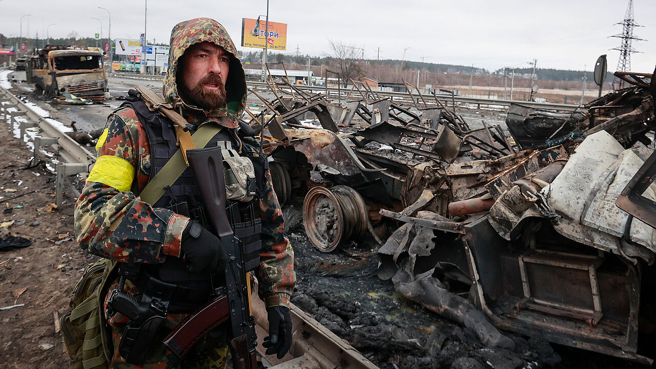 Ein Kämpfer eines ukrainischen Freiwilligenverbandes steht bei der Stadt Bucha vor ausgebrannten russischen Militärfahrzeugen. Foto: picture alliance / Associated Press / Serhii Nuzhnenko