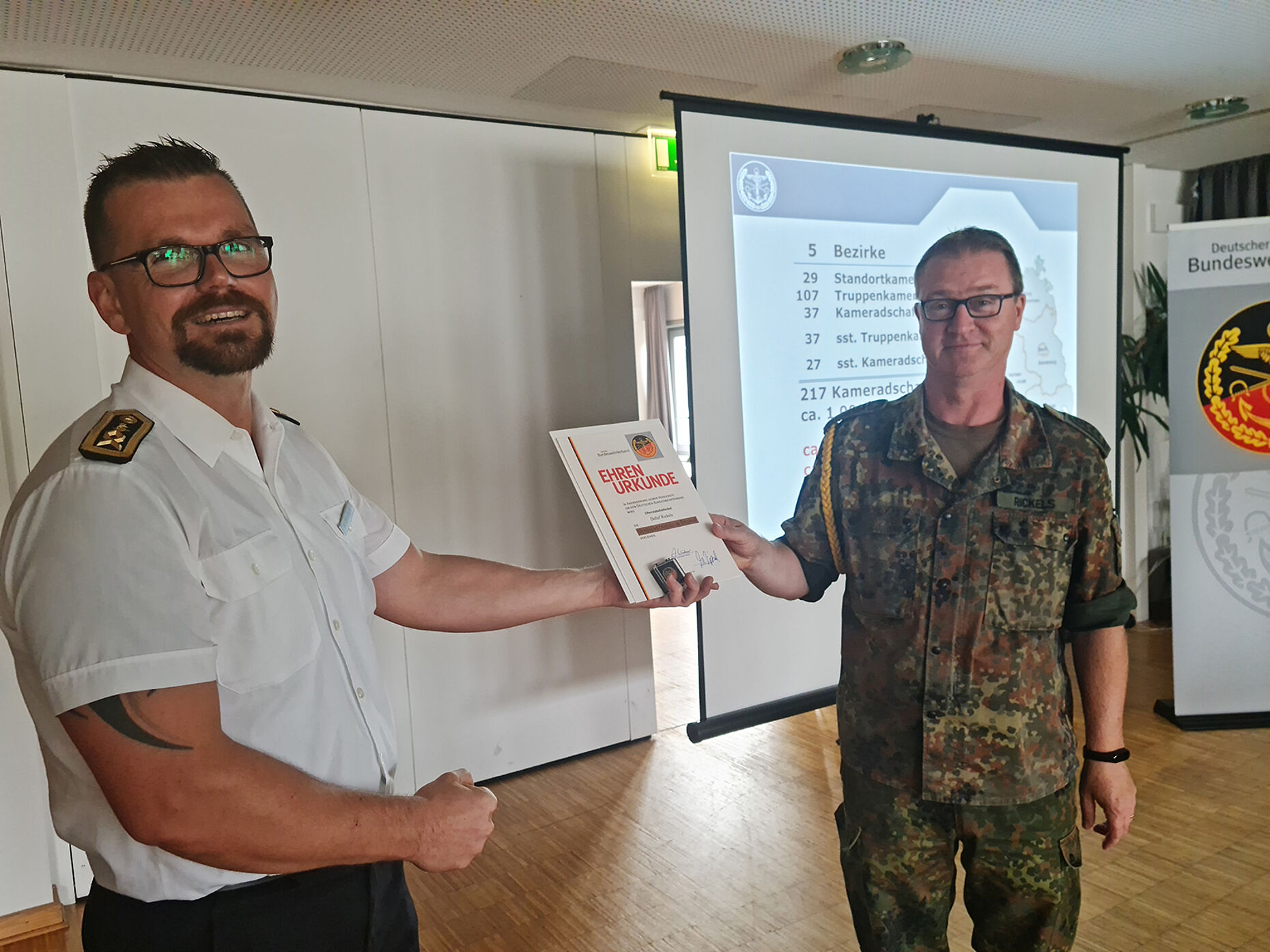 Hauptbootsmann Ebersbach (l.) verleiht Oberstabsfeldwebel Rickels die DBwV-Verdienstnadel in Bronze. Foto: DBwV/Hütten