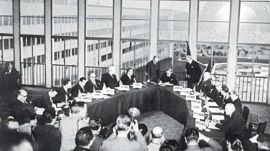 Fotografen dokumentieren den historischen Moment: der britische Außenminister Anthony Eden unterzeichnet am 23. Oktober 1954 im Palais de Chaillot die Vereinbarung zum Beitritt der Bundesrepublik Deutschland in die NATO. Foto: picture-alliance/dpa/UPI