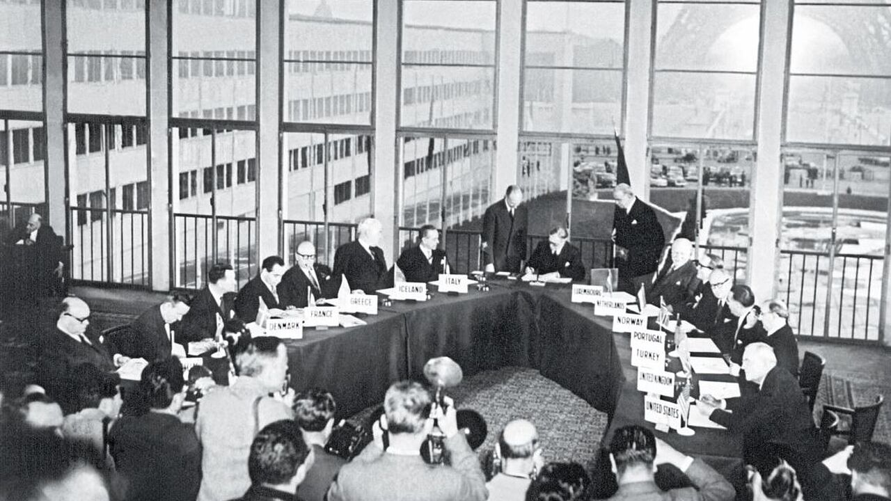 Fotografen dokumentieren den historischen Moment: der britische Außenminister Anthony Eden unterzeichnet am 23. Oktober 1954 im Palais de Chaillot die Vereinbarung zum Beitritt der Bundesrepublik Deutschland in die NATO. Foto: picture-alliance/dpa/UPI