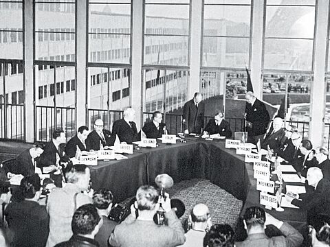 Fotografen dokumentieren den historischen Moment: der britische Außenminister Anthony Eden unterzeichnet am 23. Oktober 1954 im Palais de Chaillot die Vereinbarung zum Beitritt der Bundesrepublik Deutschland in die NATO. Foto: picture-alliance/dpa/UPI