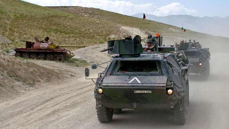 In der frühen Phase des Afghanistan-Einsatzes: Fuchs-Transportpanzer der Bundeswehr fahren am im Juni 2004 in der Nähe von Kabul an einem russischen Panzerwrack vorbei. picture-alliance/ ZB | Andreas Lander