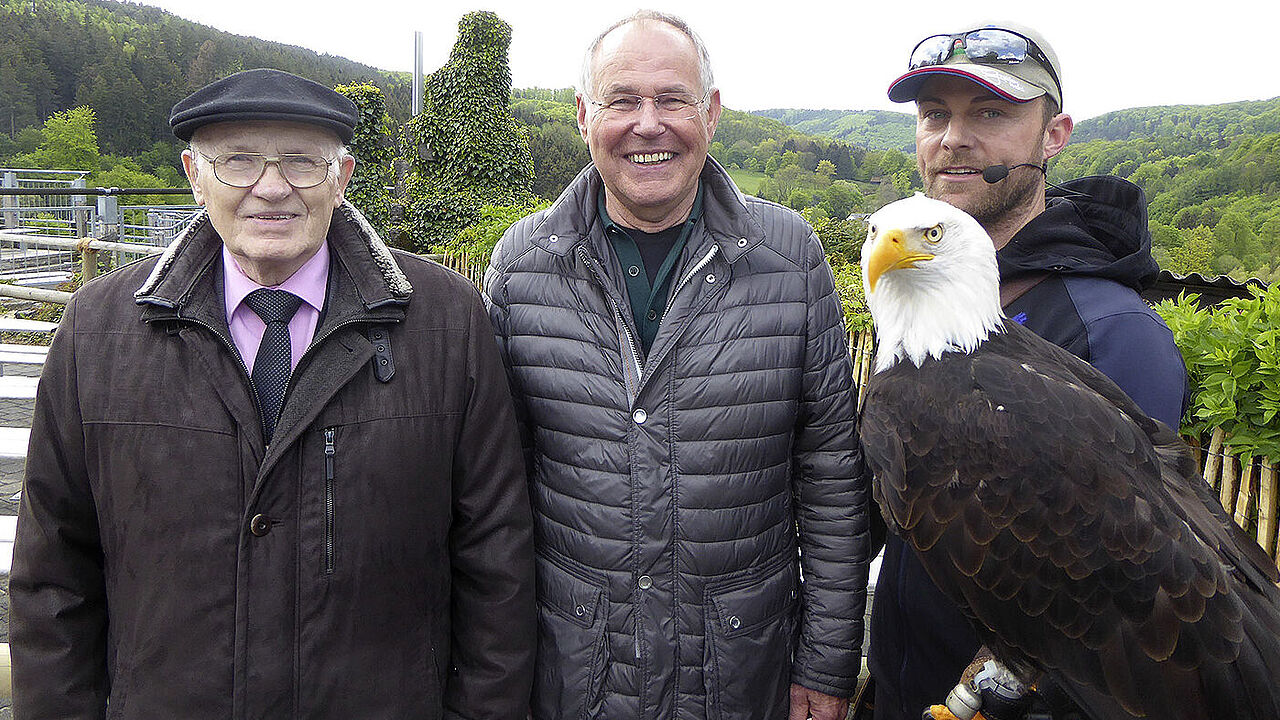 Symbolhafter hätte es nicht sein können - der Adler als Wappentier für Stärke als Kulisse für die Ehrung langjähriger Mitgliedschaft in einer starken Gemeinschaft: Albert Marx (li), Klaus Böttcher und Falkner Benjamin Aschmann mit einem Weißkopfseeadler. Foto: KERH Herrenwald/Schwalm