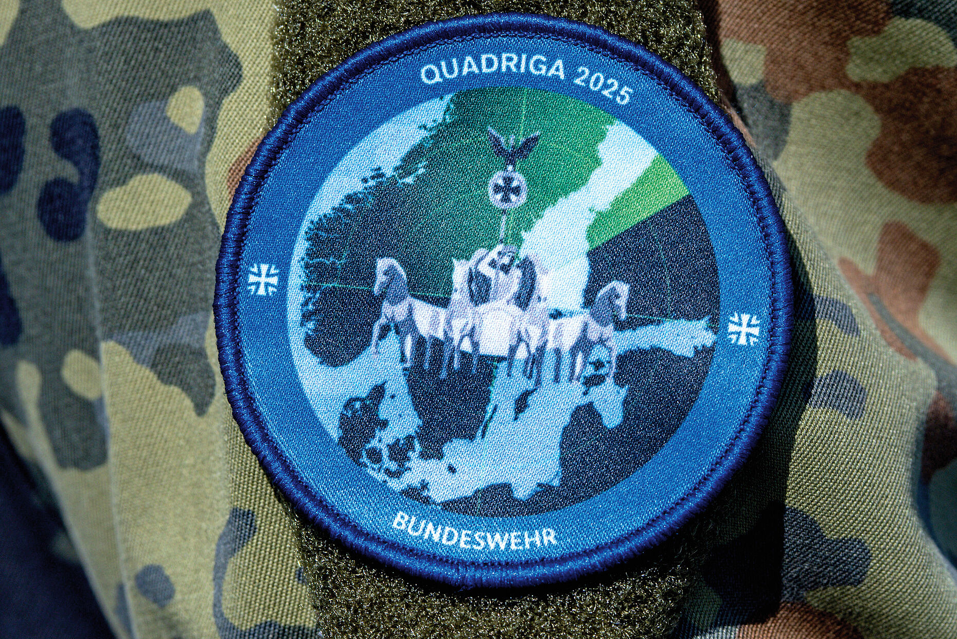 Quadriga 2025: Das Abzeichen der Militärübung „Quadriga 2025“ auf der Uniform eines Soldaten. Bei einem Übungsszenario im Hafen wird das Beladen und das Ablegen des 196 Meter langen Transportschiffs „Ark Germania“ mit Militärtechnik abgesichert. Im Rahmen des Militär-Manövers „Quadriga 2025“ werden über 1 000 Militärfahrzeuge auf dem Seeweg nach Litauen transportiert. In diesem Jahr steht die Dimension See mit der Sicherung und dem Schutz von strategischen Seewegen und Infrastrukturen im Mittelpunkt der Übungsserie „Quadriga“. Foto: picture alliance/photothek.de/Florian Gaertner