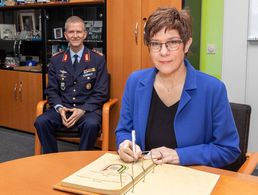 Verteidigungsministerin Annegret Kramp-Karrenbauer trägt sich unter den Augen von Generalleutnant Martin Schelleis in das Gästebuch des Kommando SKB (Streitkräftebasis) ein. Foto: Twitter/Streitkräftebasis