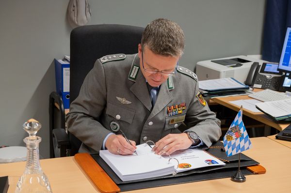 Oberst André Wüstner trägt sich nach dem Gespräch beim Kommandeur in das Gästebuch des VersBtl 4 Roding ein. Foto: RR