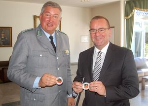 v.l.: Thomas Behr übergibt Minister Boris Pistorius eine anlässlich des Festaktes geprägte Münze („Coin“) Foto: DBwV