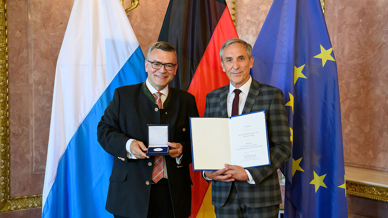Der Leiter der Bayerischen Staatskanzlei, Dr. Florian Herrmann, überreichte Stabsfeldwebel a.D. Gerhard Stärk die Medaille für Verdienste um die Zivil-Militärische Zusammenarbeit. Foto: Joerg Koch/ Bayerische Staatskanzlei