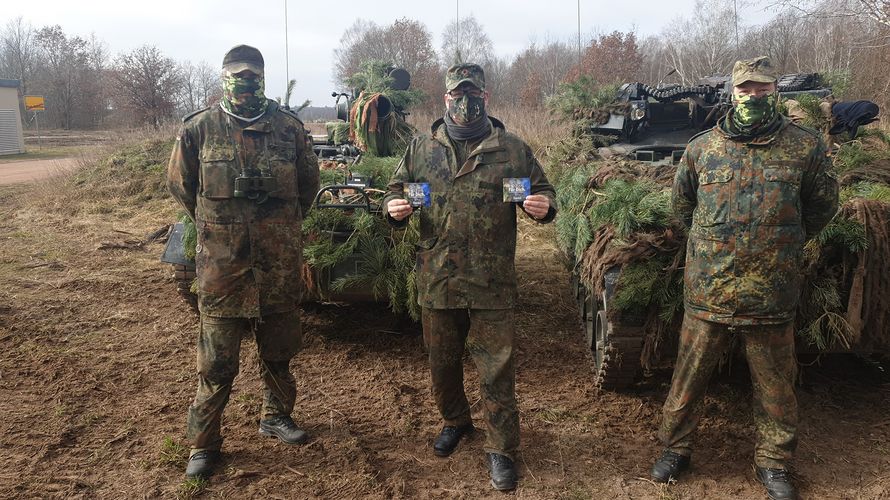 Hauptfeldwebel Sven Zietmann, Sven Stanko und Christopher Witzak (v.l.) während der Mittagspause auf dem Truppenübungsplatz Altmark vor ihren Waffenträgern WIESEL TOW und WIESEL MK. Foto: DBwV/Frome