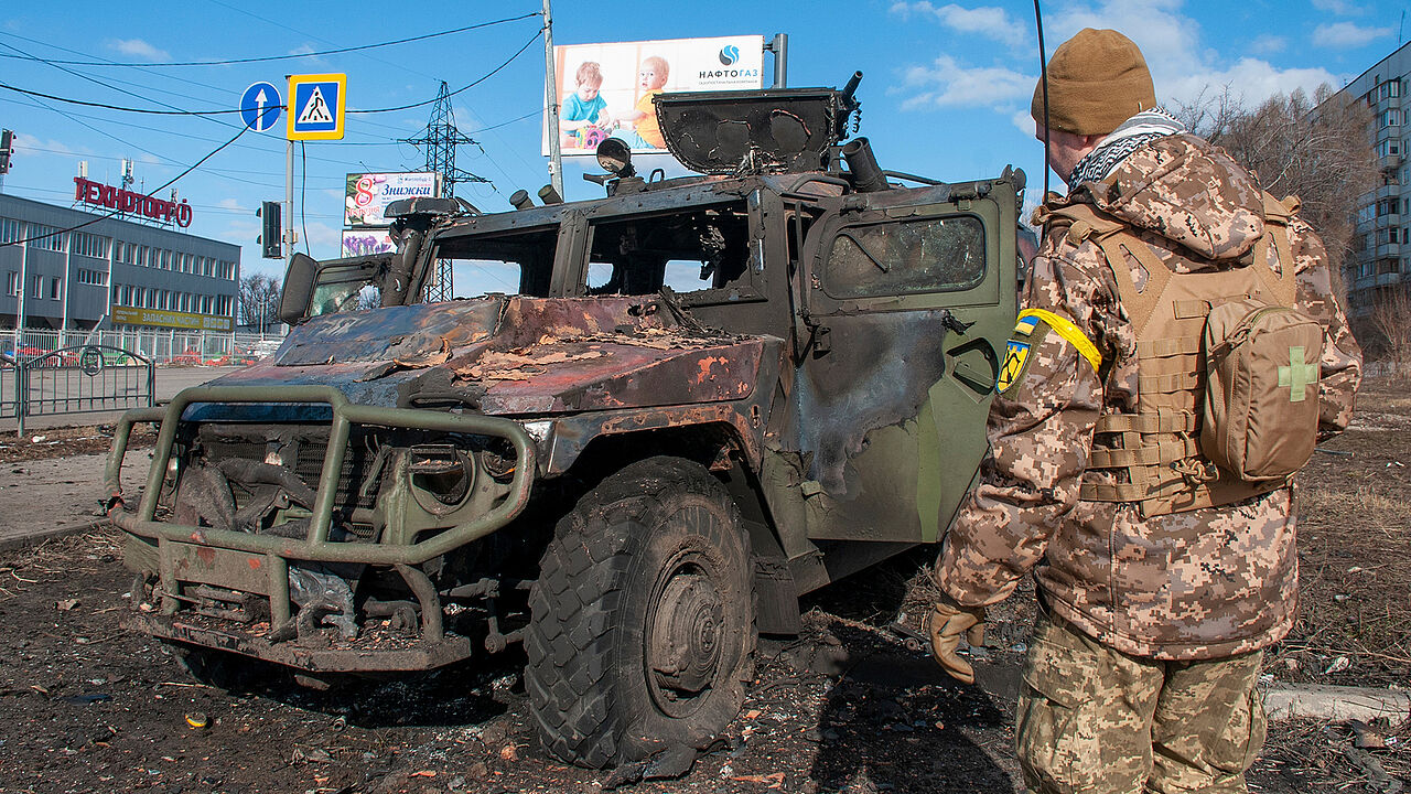 In Charkiw steht ein ukrainischer Soldat vor einem zerstörten russischen Fahrzeug. Seit einer Woche ist Krieg in Europa. Foto: picture alliance / Associated Press / Marienko Andrew