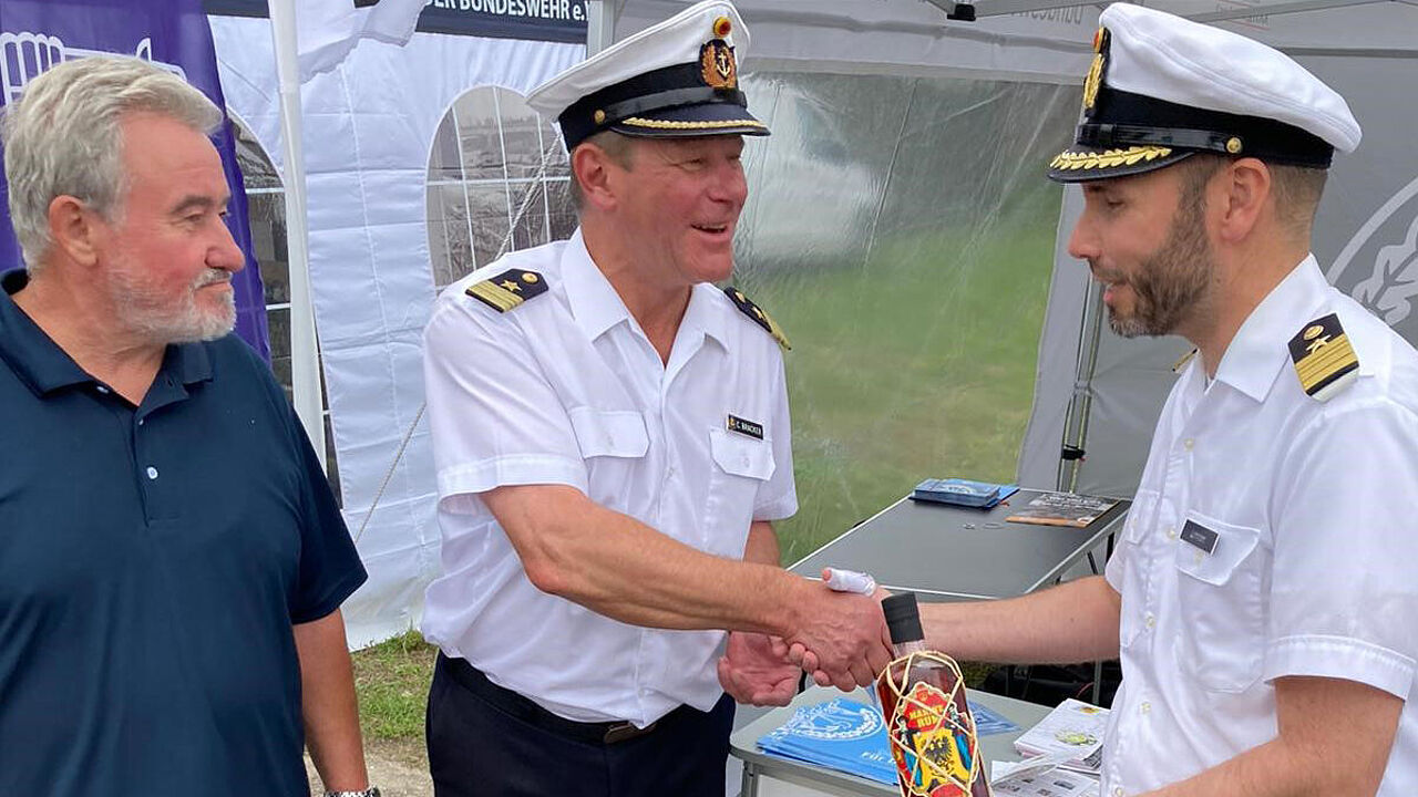 Mit einer Flasche Rum, der speziell zum 175-jährigen Jubiläum der Deutschen Marine hergestellt wurde, bedankte sich Kapitänleutnant Carsten Bracker (M.) beim Stützpunktkommandanten, Fregattenkapitän Robert Lehmann (r). Foto: Olaf Pietrzak