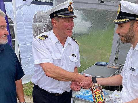 Mit einer Flasche Rum, der speziell zum 175-jährigen Jubiläum der Deutschen Marine hergestellt wurde, bedankte sich Kapitänleutnant Carsten Bracker (M.) beim Stützpunktkommandanten, Fregattenkapitän Robert Lehmann (r). Foto: Olaf Pietrzak