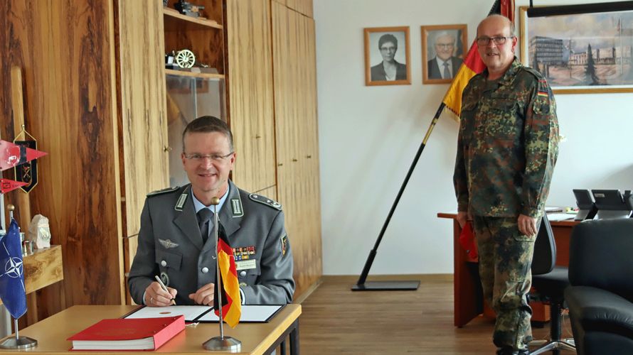 Oberstleutnant André Wüstner trägt sich in das Gästebuch der Artillerieschule ein, rechts daneben Oberst Dietmar Felber. Foto: ArtS