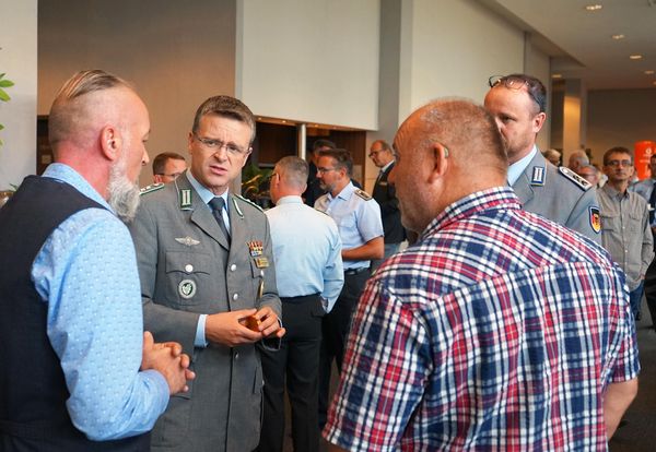 Oberst André Wüstner (2.v.l) unterhält sich in einer Tagungspause mit Delegierten der Tagung auf Bezirksbene des Landesverbands Ost.  Foto: DBwV/Kruse