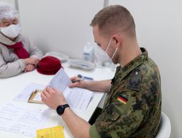 Ein Fliegerarzt führt im Januar 2021 mit der zu impfenden Person ein Vorgespräch im Corona-Impfzentrum am Flughafen BER in Schönefeld. Nun kommen wieder Soldaten der Bundeswehr in Berliner Impfzentren zum Einsatz. Archivfoto: Bundeswehr/Tom Twardy