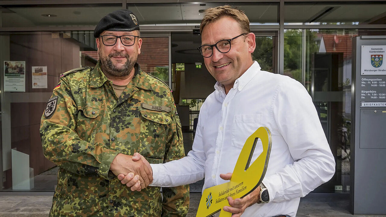 Brigadegeneral André Abed übergibt die Gelbe Schleife an den Bürgermeister von Güntersleben Michael Freudenberger. Foto: Robert Issing/Fotofreunde Güntersleben