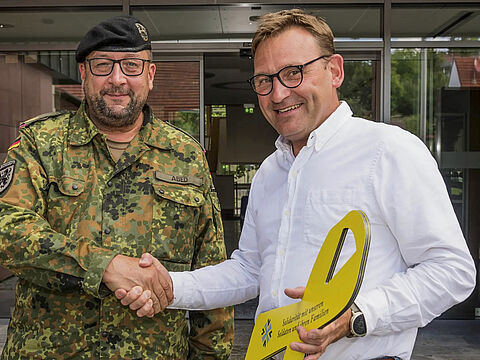 Brigadegeneral André Abed übergibt die Gelbe Schleife an den Bürgermeister von Güntersleben Michael Freudenberger. Foto: Robert Issing/Fotofreunde Güntersleben
