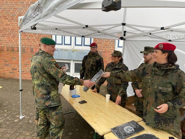 Oberfeldwebel Julia-Maleika Felske (r.), Beisitzerin der Standortkameradschaft Neustadt-Luttmersen, übergibt einem Mitglied ein ausgesuchtes Giveway. Alle Beteiligten waren sichtlich erfreut. Foto: R.Neser/DBwV