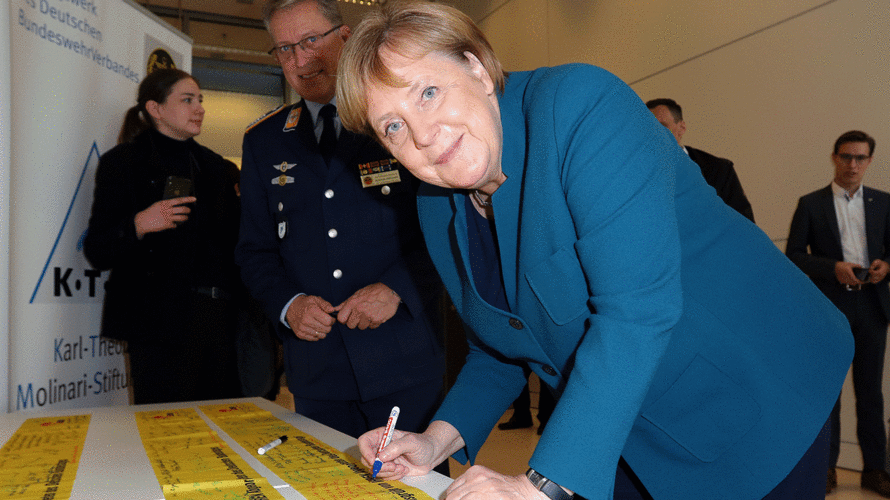Bundeskanzlerin Angela Merkel unterzeichnet ein Gelbes Band. Foto: DBwV/Mika Schmdt