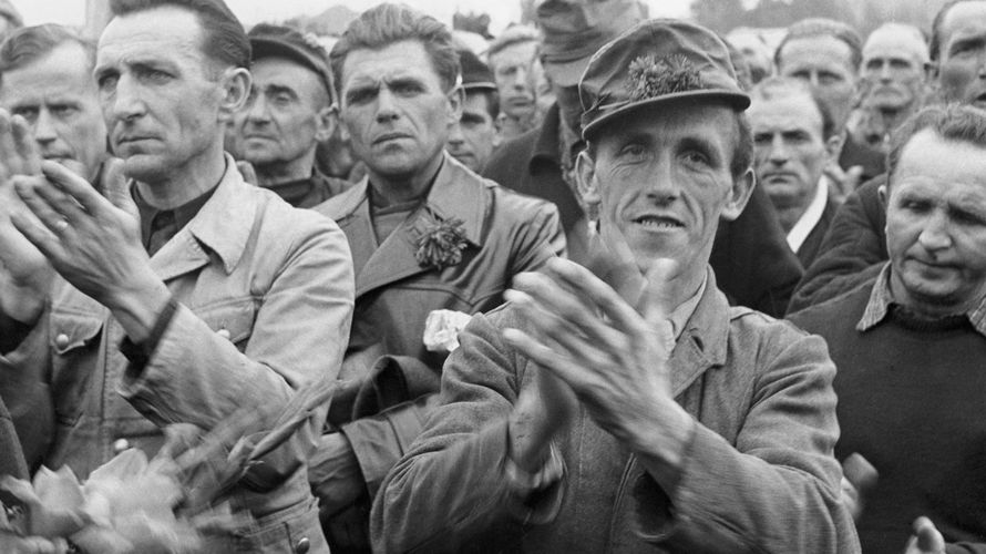 Aus sowjetischer Kriegsgefangenschaft heimgekehrte Männer applaudieren während ihre Begrüßung im Lager Friedland (Archivfoto vom 09.10.1955).