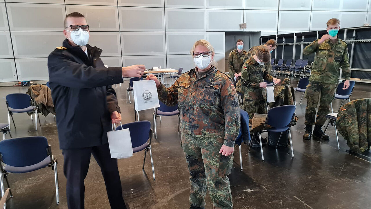Hauptbootsmann Ebersbach (l.) und Hauptbootsmann Stern verteilen ein kleines Dankeschön an die engagierten Einsatzkräfte. Foto: DBwV/ Pietrzak