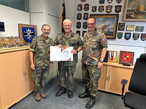 Oberstleutnant Dr. Linus Strelau und der Vorsitzende Sanitätsdienst Oberstabsfeldwebel Stefan Sprengers überreichten Generaloberstabsarzt Dr. Ralf Hoffmann die Treueurkunde. Foto: HptFw René Riedel