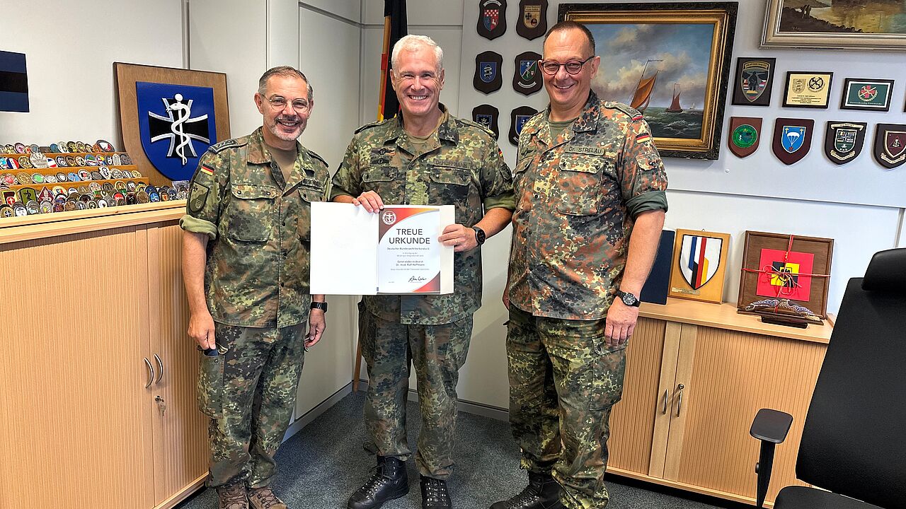 Oberstleutnant Dr. Linus Strelau und der Vorsitzende Sanitätsdienst Oberstabsfeldwebel Stefan Sprengers überreichten Generaloberstabsarzt Dr. Ralf Hoffmann die Treueurkunde. Foto: HptFw René Riedel