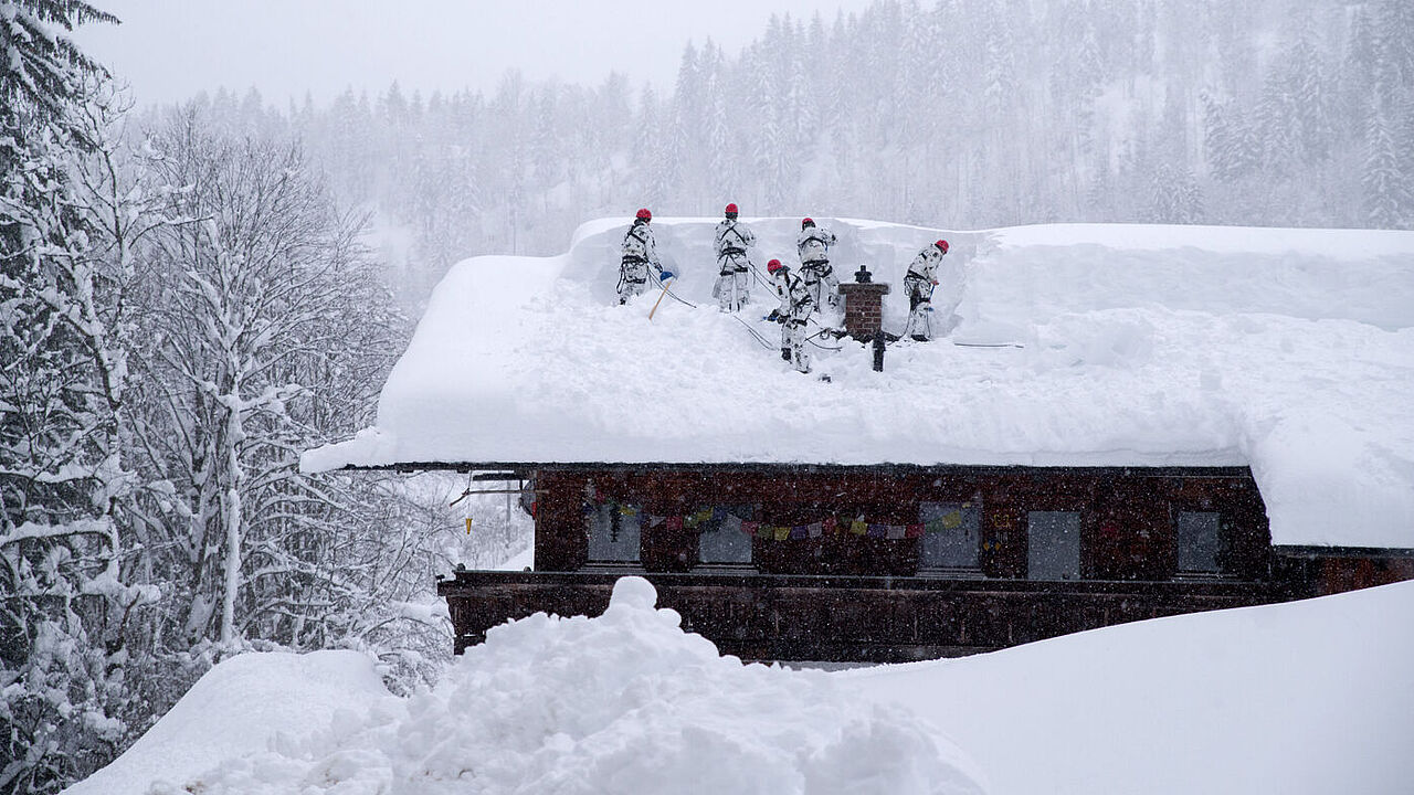 Dramatische Lage: Auf den Dächern steht der Schnee mannshoch - es besteht Einsturzgefahr. Gebirgsjäger befreien die Häuser von der weißen Last. Foto: DBwV/Bombeke