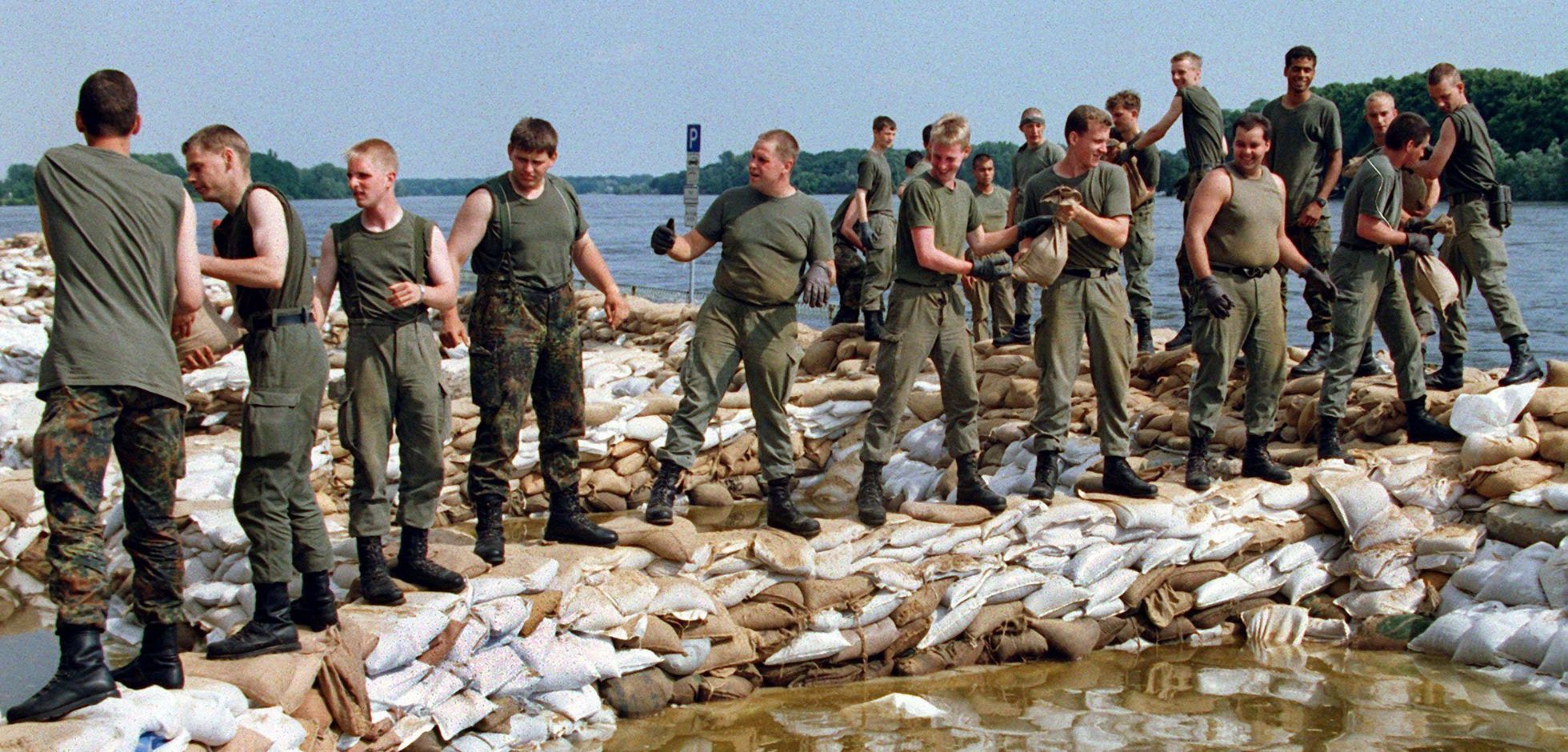 Pausenlos stapeln Bundeswehrsoldaten am 27.7.1997 in Frankfurt (Oder) Sandsäcke, um den künstlichen Deich an der Oder zu erhöhen. Die Hilfskräfte von Bundeswehr, Bundesgrenzschutz, Technischem Hilfswerk (THW) und der freiwilligen Feuerwehren arbeiten im Hochwassergebiet Hand in Hand. Foto: dpa/Wolfgang Kumm