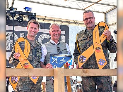 Ein sichtbares Zeichen der Verbundenheit: Kompaniechef Major Kevin H. (von links), Bürgermeister Georg Hoffmann und Kompaniefeldwebel Oberstabsfeldwebel Tobias M. nach der Übergabe der Gelben Schleife und des Kompaniewappens. Foto: tm