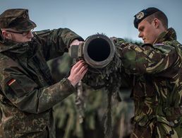 Ein Kampfpanzer des binationalen Panzerbataillons 414 wird von einem deutschen und einem niederländischen Soldaten für den Einsatz vorbereitet.
