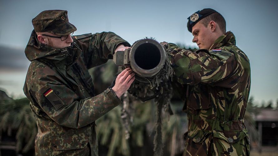 Ein Kampfpanzer des binationalen Panzerbataillons 414 wird von einem deutschen und einem niederländischen Soldaten für den Einsatz vorbereitet.