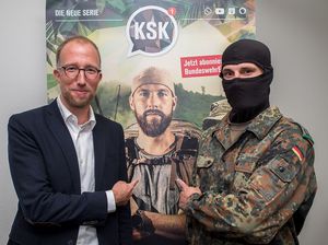 Dirk von Holleben (r.) und Oberstleutnant Ben, in der Mitte auf de Plakat ist Robert Marc Lehmann zu sehen. Foto: DBwV/Bombeke 