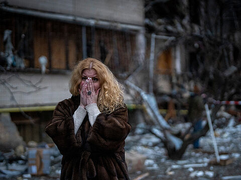 Fassungslos steht eine Ukrainerin vor den Trümmern eines Wohnblocks in Kiew, der in der Nacht bei einem russischen Raketenangriff zerstört wurde. picture alliance / ASSOCIATED PRESS / Emilio Morenatti