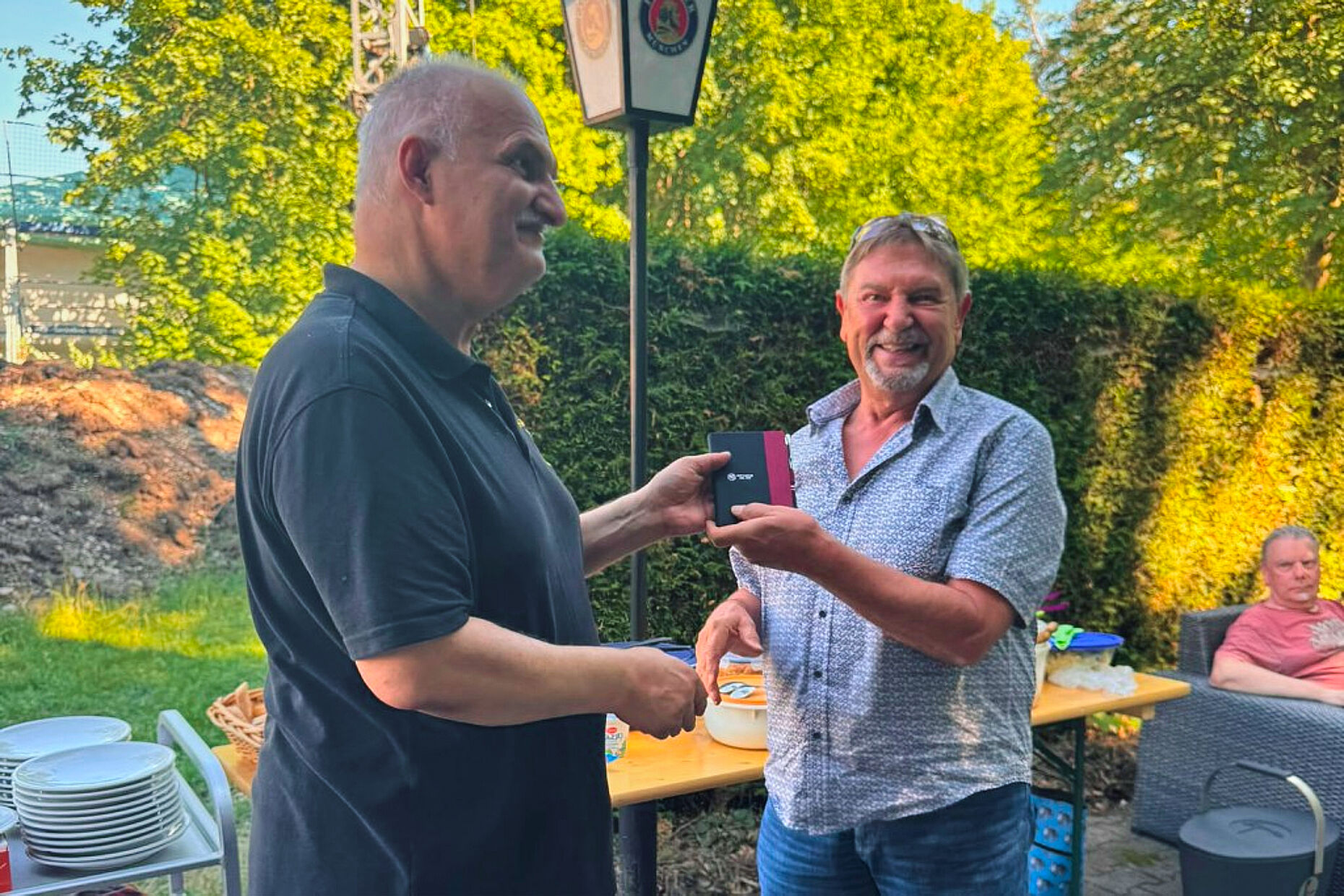Vorsitzender Michael Lipp dankt Kantinenpächter Thomas Schipf mit einer druckfrischen Jubiläumsgabe des Notizbuches zu „40 Jahre KERH Augsburg“. Foto: li