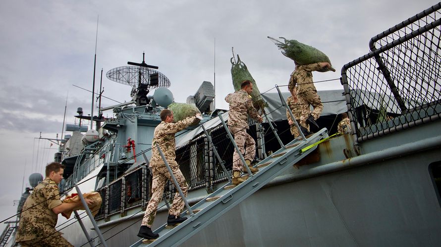 Soldaten tragen aus Deutschland geschickte Weihnachtsbäume auf die „Mecklenburg-Vorpommern“ Foto: dpa