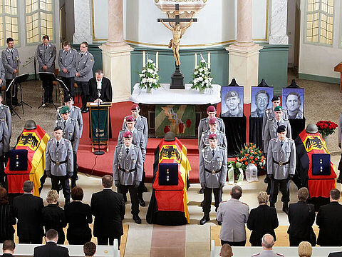Trauer-Gottesdienst in Bad Salzungen 2009: Hinter den Särgen der Hauptgefreiten Martin Brunn (r.), Alexander Schleiernick (M.) und Oleg Meiling (l.) stehen Bilder der Soldaten. Foto: dpa 