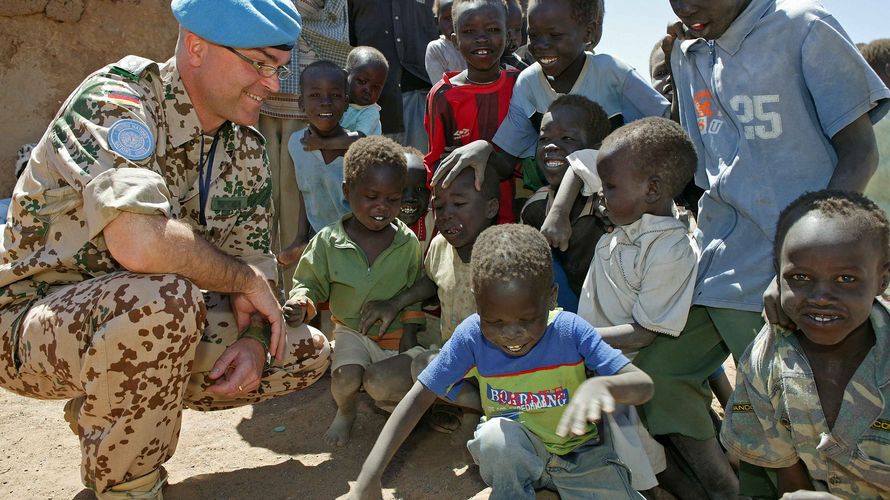 Symbolbild: Ein Oberstleutnant unterhält sich im April 2006 mit Flüchtlingskindern im Binnenflüchtlingslager Jebel Aulia. Foto: Bundeswehr/Rott 