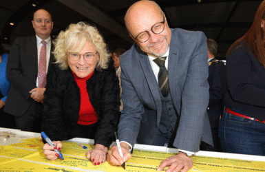 Die Justizministerin Christine Lambrecht und der Abgeordnete Fritz Felgentreu (beide SPD) unterschreiben ein Gelbes Band. Foto: DBwV/Mika Schmidt