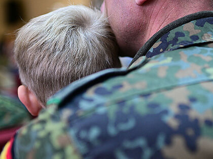 Ein Soldat sitzt während der Eröffnung der Deutschen Schule Vilnius mit seinem Sohn im Publikum. Kinder von Bundeswehrangehörigen im Ausland werden bei der jetzt beschlossenen Frühstartrente nicht berücksichtigt. Foto: picture alliance/dpa/Sebastian Gollnow