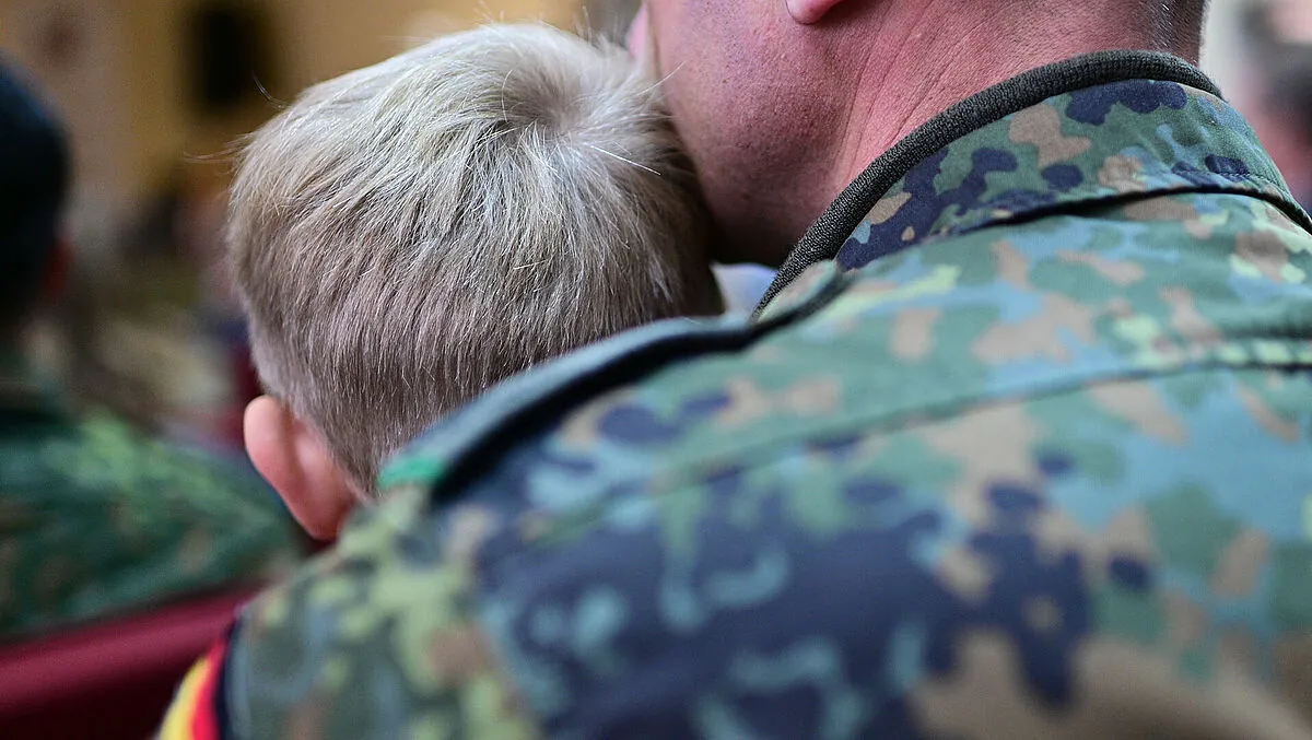 Ein Soldat sitzt während der Eröffnung der Deutschen Schule Vilnius mit seinem Sohn im Publikum. Kinder von Bundeswehrangehörigen im Ausland werden bei der jetzt beschlossenen Frühstartrente nicht berücksichtigt. Foto: picture alliance/dpa/Sebastian Gollnow
