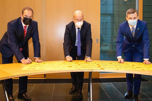 Die Unionspolitiker Henning Otte, Ralph Brinkhaus und Thomas Silberhorn (v.l.n.r.) unterzeichnen ein Gelbes Band. Foto: DBwV/Mika Schmidt