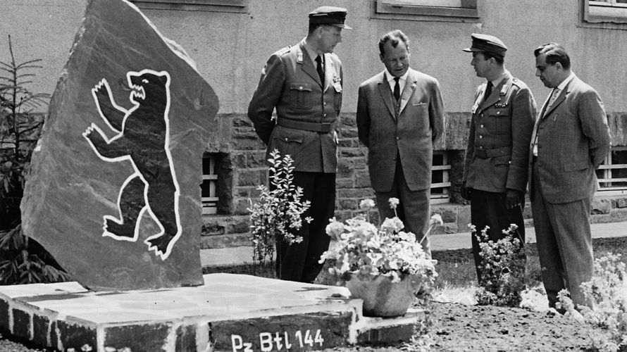 Oberst Karl-Theodor Molinari (links) zeigt dem Regierenden Bürgermeister Berlins, Willy Brandt (2.v.l.), bei seinem Truppenbesuch am 21. Juni 1961 in der Gneisenau-Kaserne in Koblenz den großen Mahnstein mit dem Berliner Wappentier. Foto: DBwV/Archiv