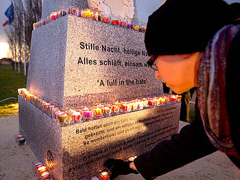 Ein Schüler legt eine Kerze am Denkmal ab, das im belgischen Mesen an den Weihnachtsfrieden von 1914 erinnert. Foto: picture alliance/AP Photo/Virginia Mayo