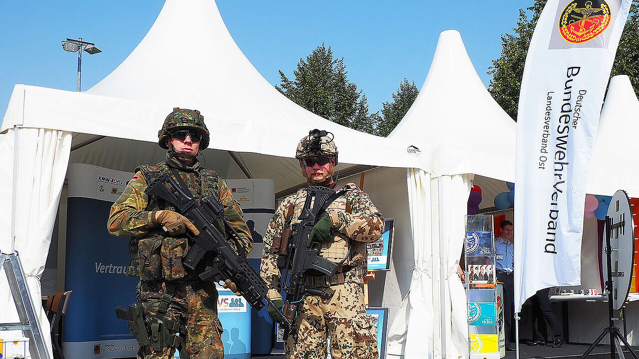 Ein Soldat des Seebataillons (l.) und en Soldat mit der Ausrüstung "Infanterist der Zukunft" stehen vor dem Stand des DBwV. Foto: DBwV/Kruse