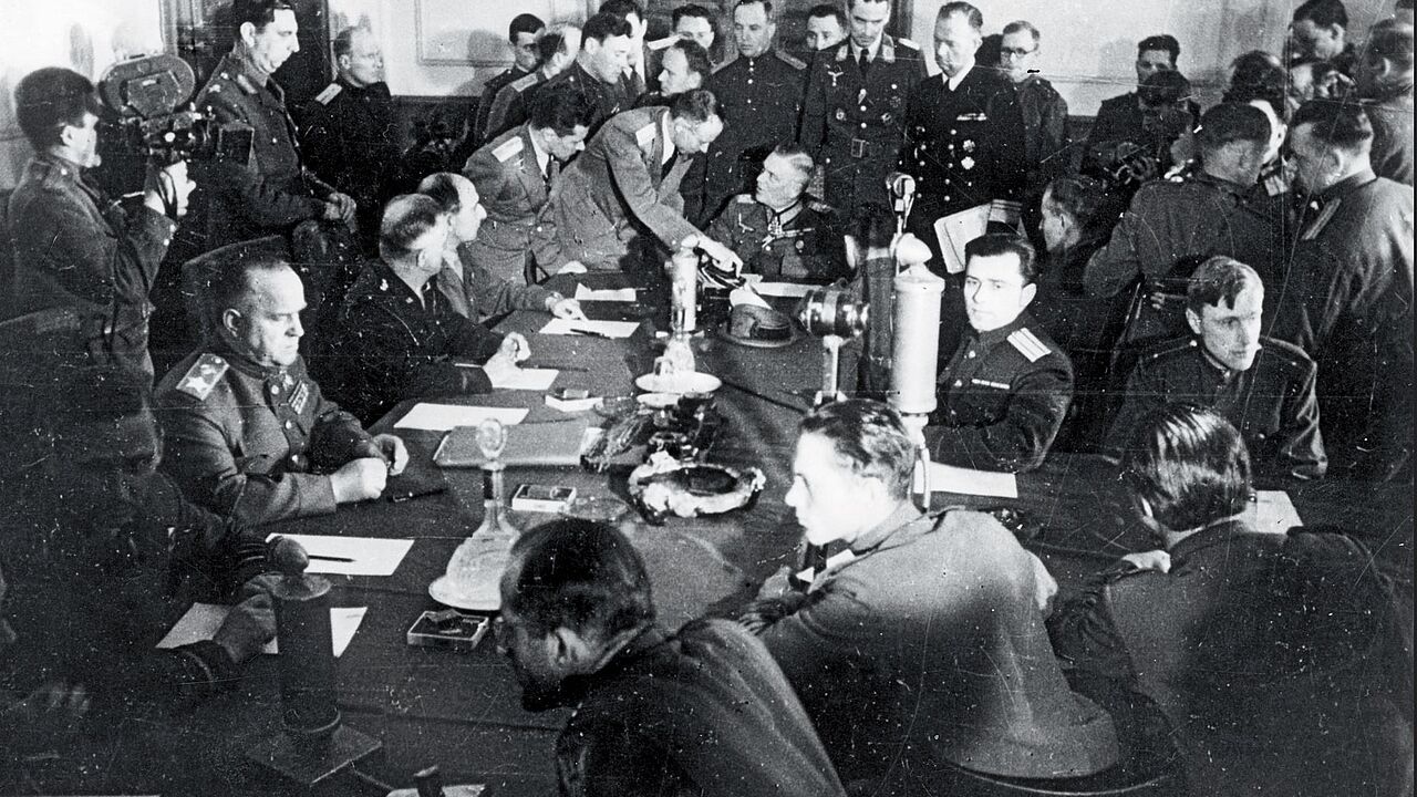 Blick in den Raum während der Unterzeichnung der Kapitulation in Berlin-Karlshorst. Links am Tisch der sowjetische Marschall Georgi Schukow, am Kopfende Generalfeldmarschall Wilhelm Keitel. Foto: dpa/Picture Alliance 