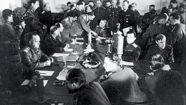 Blick in den Raum während der Unterzeichnung der Kapitulation in Berlin-Karlshorst. Links am Tisch der sowjetische Marschall Georgi Schukow, am Kopfende Generalfeldmarschall Wilhelm Keitel. Foto: dpa/Picture Alliance 