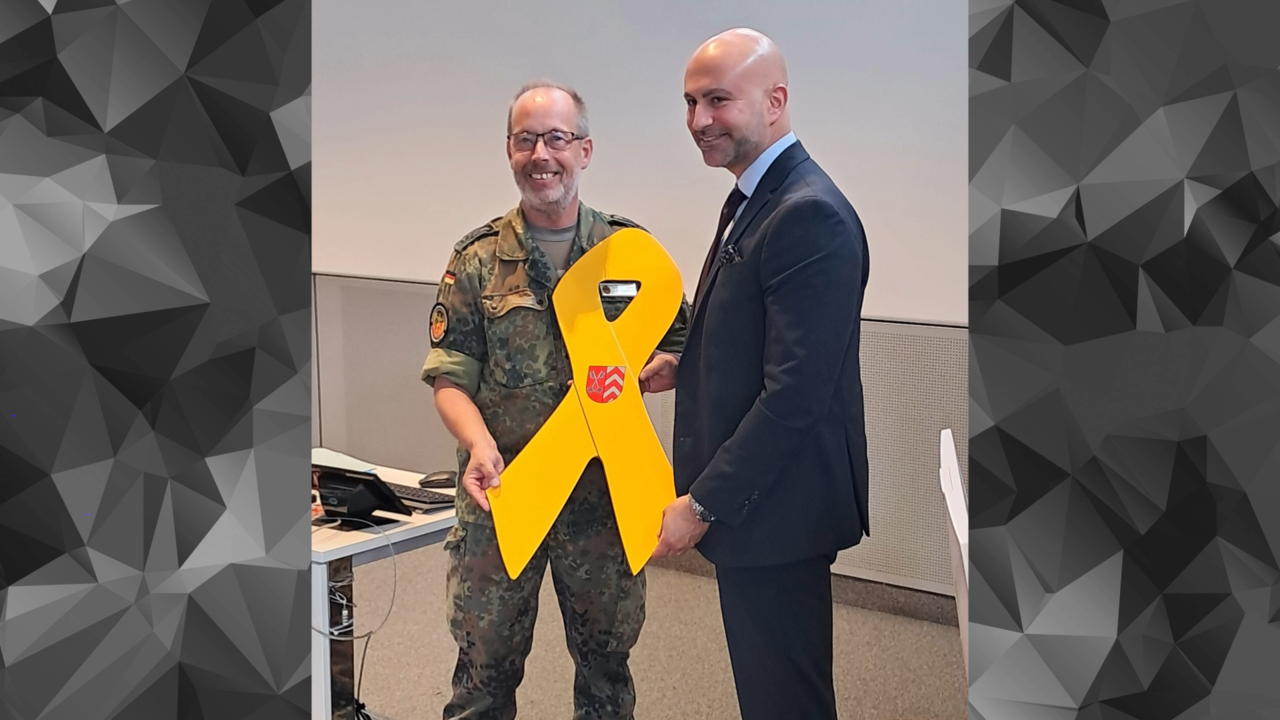 Anlässlich des 2. Veteranentages überreichte der Landesvorsitzende West, Stabsfeldwebel Volker Keil, die Gelbe Schleife an Landrat Ali Dogan (SPD). Foto: DBWV