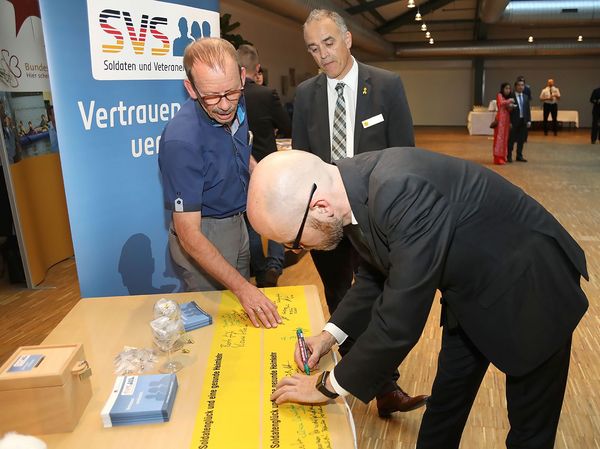 Staatssekretär Peter Tauber setzte im Beisein von Oberstabsfeldwebel a.D. Jürgen Görlich mit seiner Unterschrift auf einem Gelben Band ein Zeichen der Solidarität mit den Soldaten im Einsatz. Foto: UK-BMVg/Grauwinkel