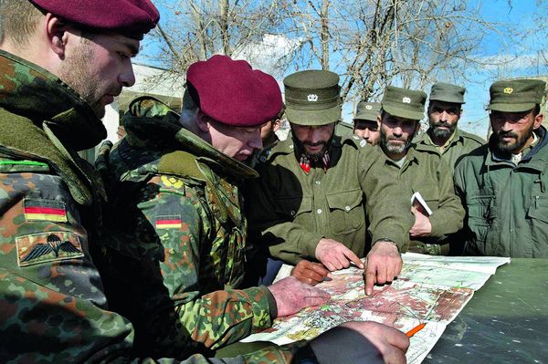 Der Kommandeur der Bundeswehr-Vorauskommandos, Brigadegeneral Carl Hubertus von Butler (2.v. l.), studiert im Januar 2002 gemeinsam mit afghanischen Polizisten eine Karte von Kabul, bevor deutsche Soldaten und afghanische Polizisten gemeinsam durch einen Vorort von Kabul patrouillieren. Foto: dpa/Anja Niedringhaus